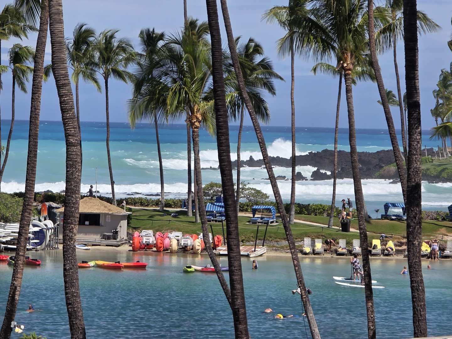 Calm protected lagoon with kayaks in the foreground and heavy whitewater breaking on the reef beyond